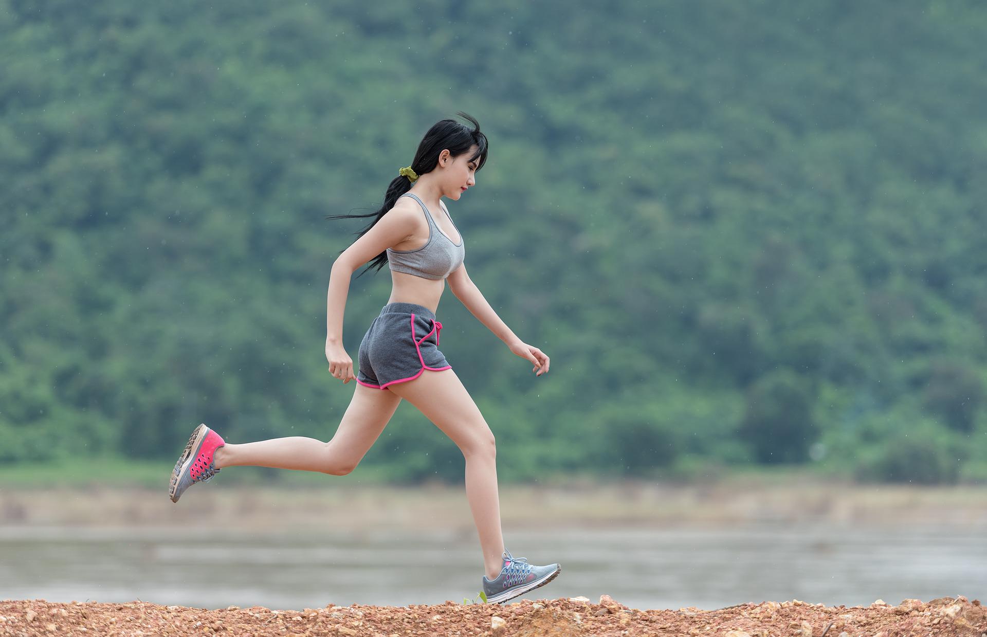 thletic woman in sports bra and shorts jogging outdoors.